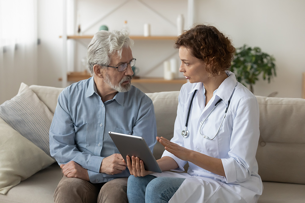Doctor and patient sit on couch discussing potential outcomes of medical treatment.